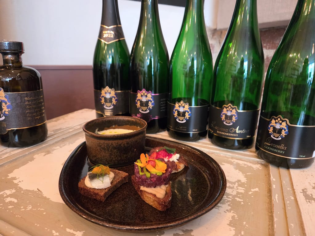 Tarkiainen Wineryn viinipulloja, edessä ravintola SKördin annos.