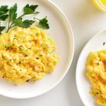 Kaksi lautasta, joilla munakokkelia. Päällä persiljaa.